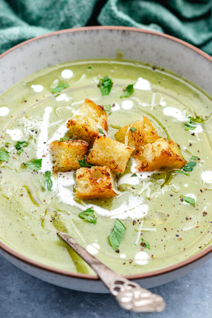 The soup in a bowl topped with croutons, cream and parmesan cheese.