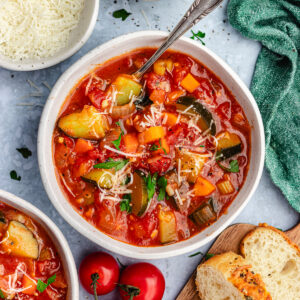 The soup in two small bowls topped with parmesan and parsley.