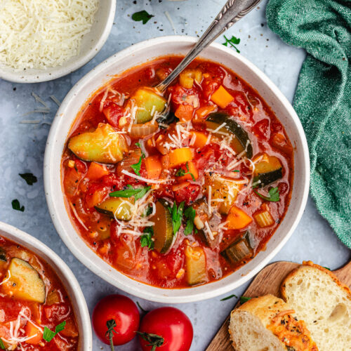The soup in two small bowls topped with parmesan and parsley.