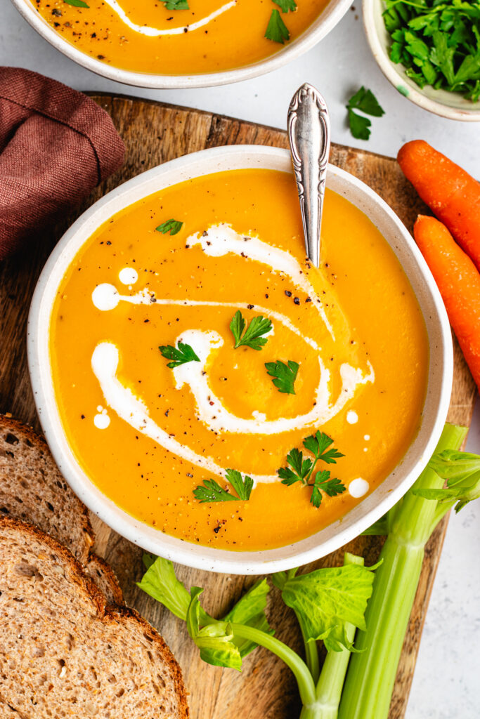 The soup in a bowl topped with some coconut milk and parsley.
