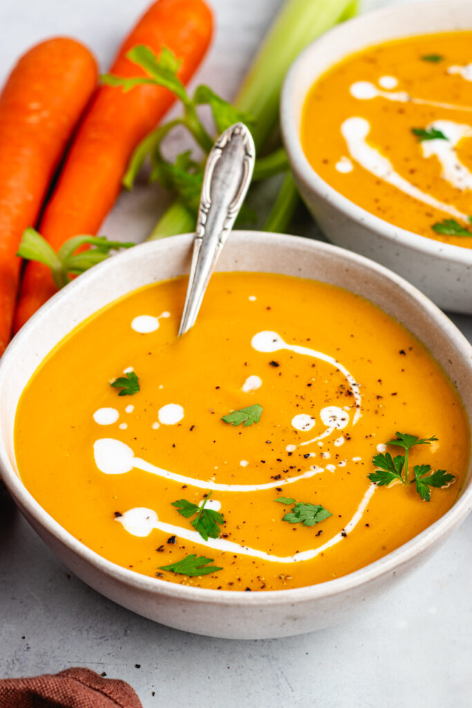 The soup in a bowl topped with some coconut milk and parsley.