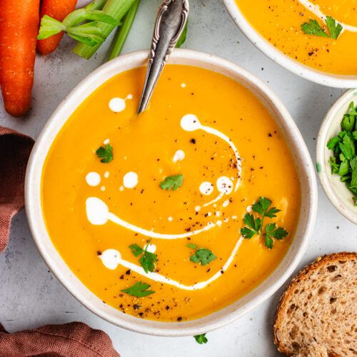 The soup in a bowl topped with some coconut milk and parsley.