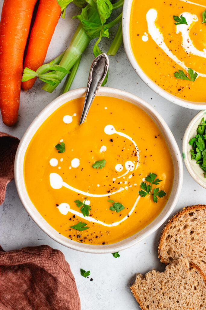 The soup in a bowl topped with some coconut milk and parsley.
