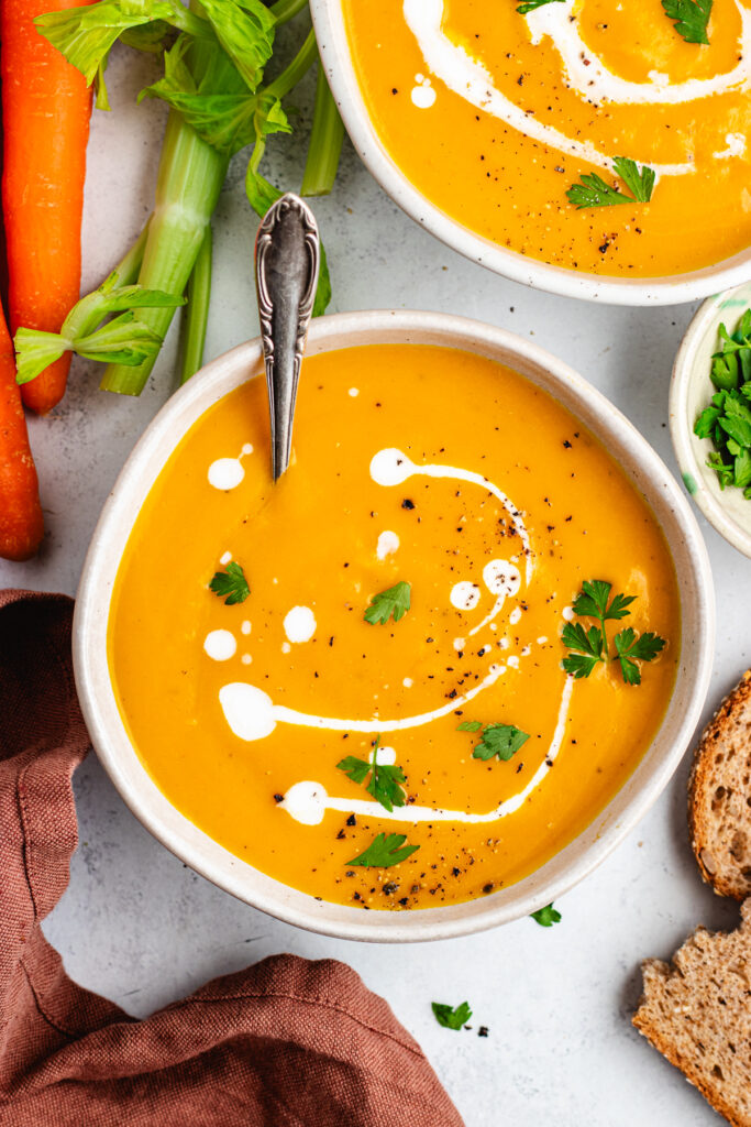 The soup in a bowl topped with some coconut milk and parsley.