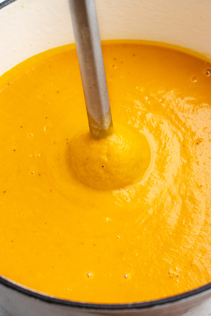 Blending the soup with an immersion blender.