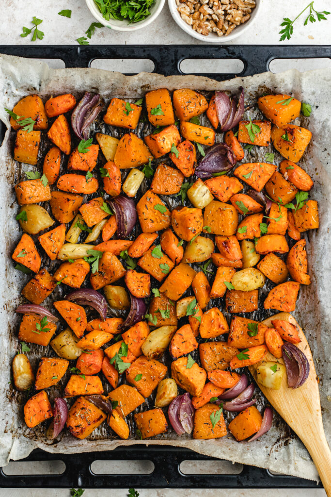 The roasted vegetables in the sheet pan topped with chopped parsley. 