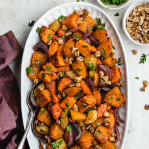 The roasted vegetables on o serving platter topped with chopped parsley and walnuts.