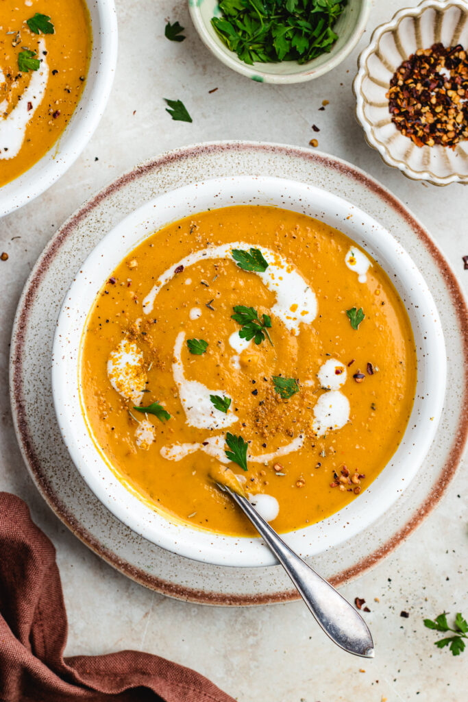 The soup inn a bowl topped with cream, chopped parsley and spices.