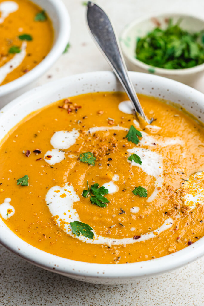 The soup in a bowl topped with cream, chopped parsley and spices.