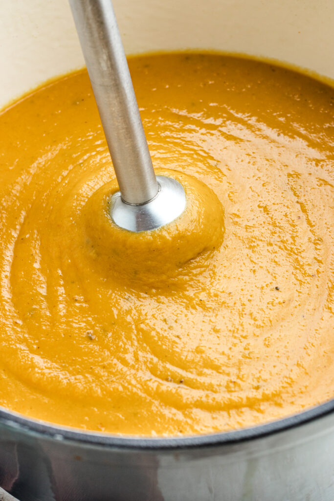 Blending the soup with an immersion blender.