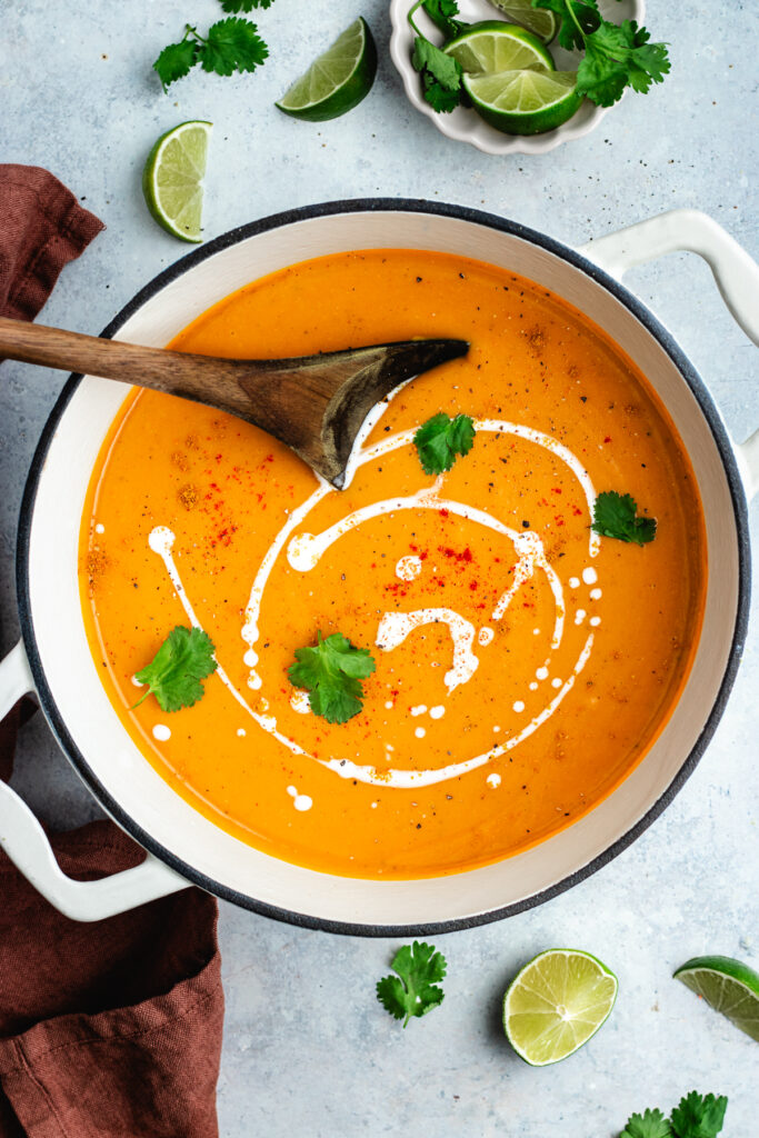 The finished soup in the pot topped with a drizzle of cream and herbs.