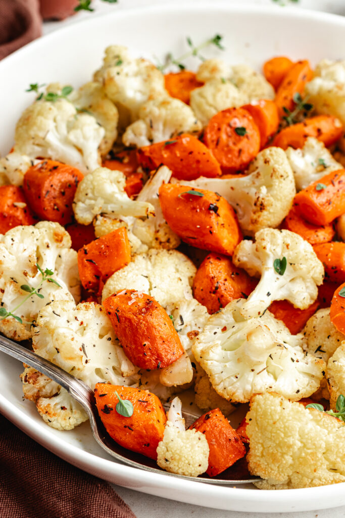 The roasted vegetables on a serving platter topped with fresh thyme.
