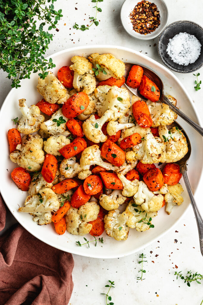 The roasted vegetables on a serving platter topped with fresh thyme.