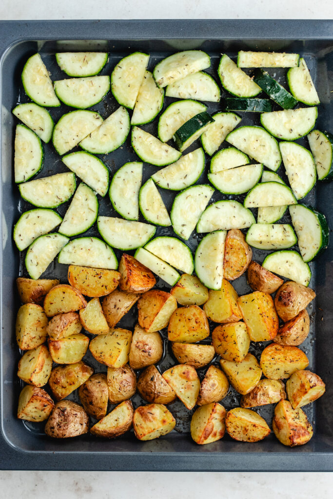 The potatoes and zucchini on the sheet pan.