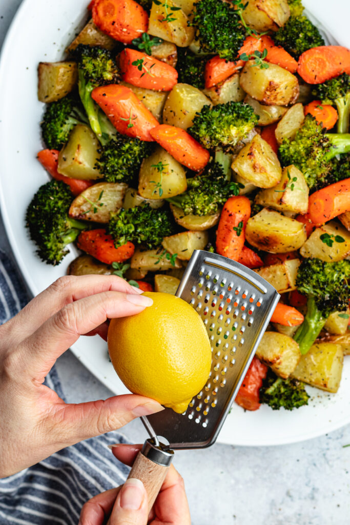 Topping the roasted veggies with lemon zest.