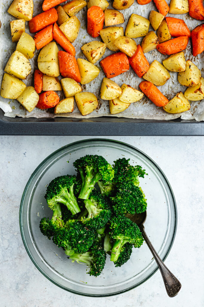 The broccoli in a bowl and the roasted potatoes and carrots on the sheet pan.