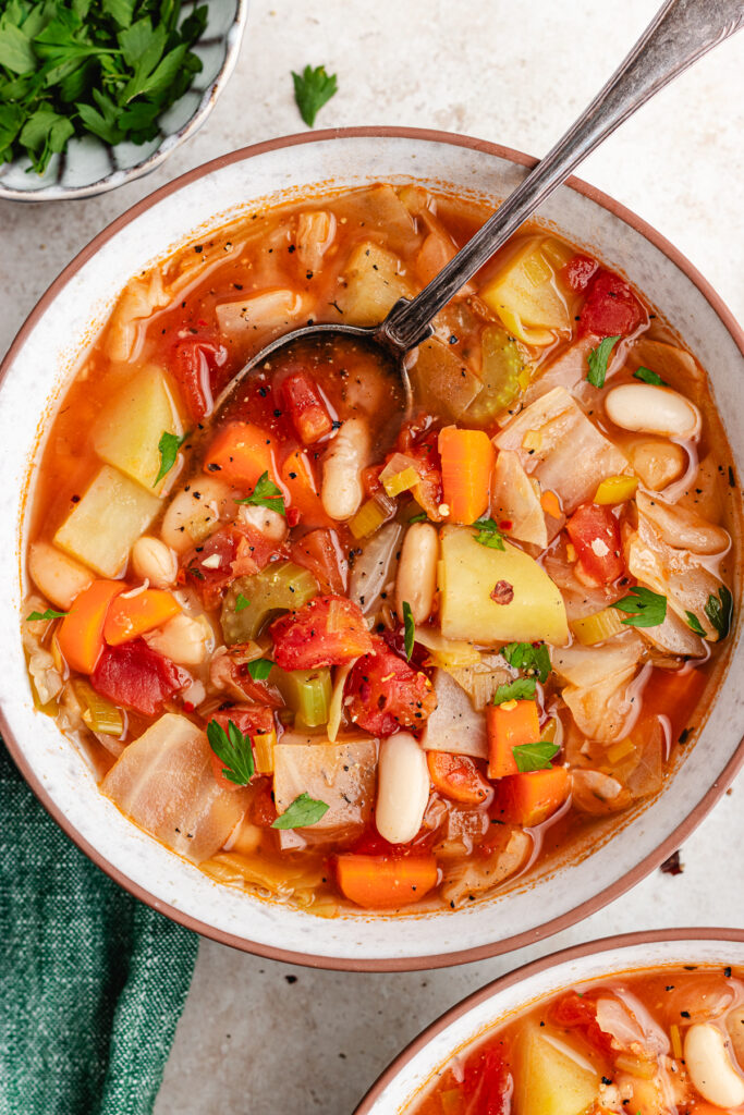 Two bowls of soup topped with fresh herbs.
