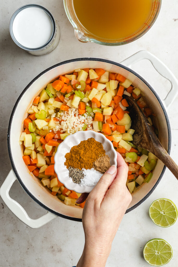 The sautéed vegetables in a soup pot with garlic and spices.