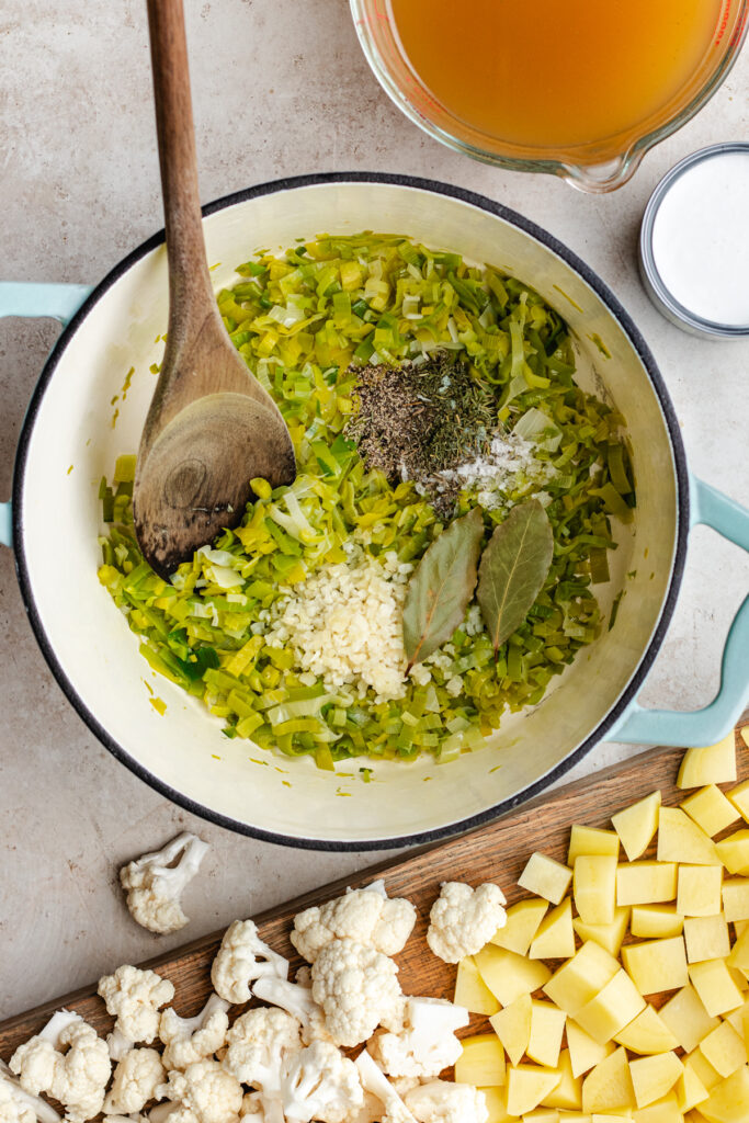 The sautéed leek in a soup pot with the garlic and spices.