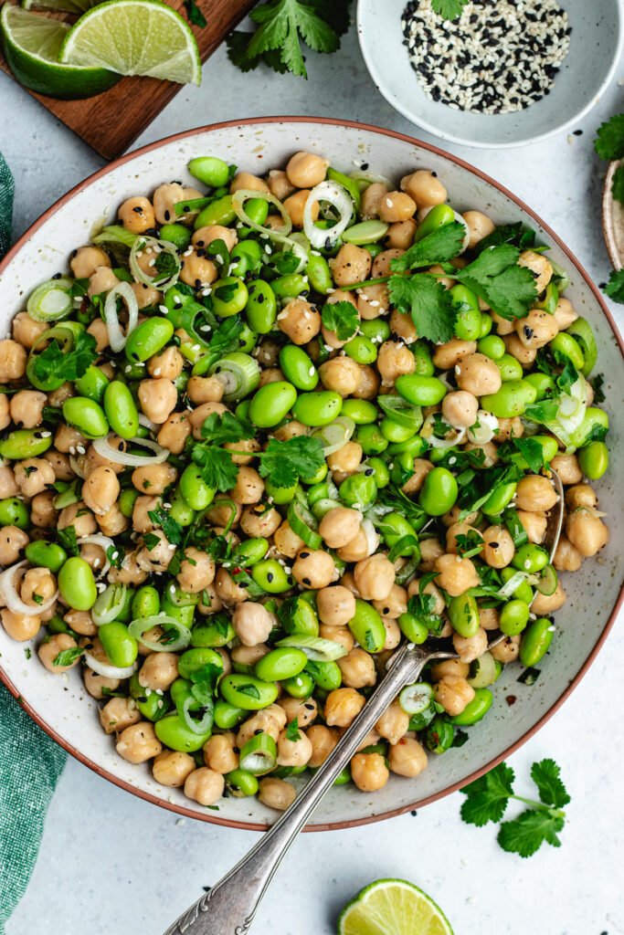 The edamame and chickpeas salad in a bowl, topped with fresh herbs and sesame seeds. 
