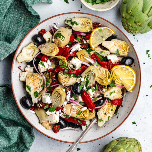The artichoke salad in a bowl topped with lemon slices.