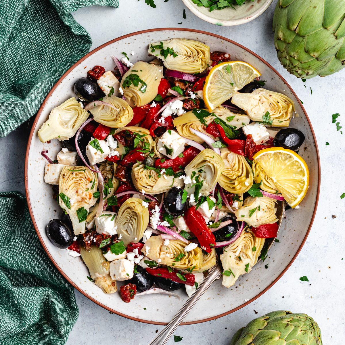 The artichoke salad in a bowl topped with lemon slices.