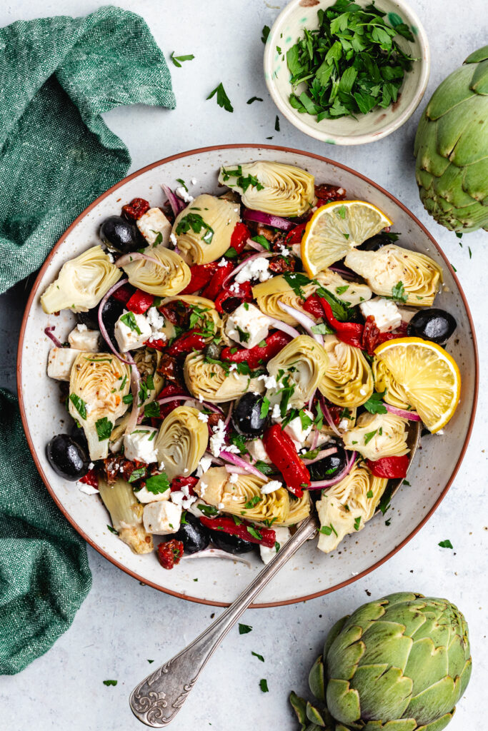 The artichoke salad in a bowl topped with lemon slices.