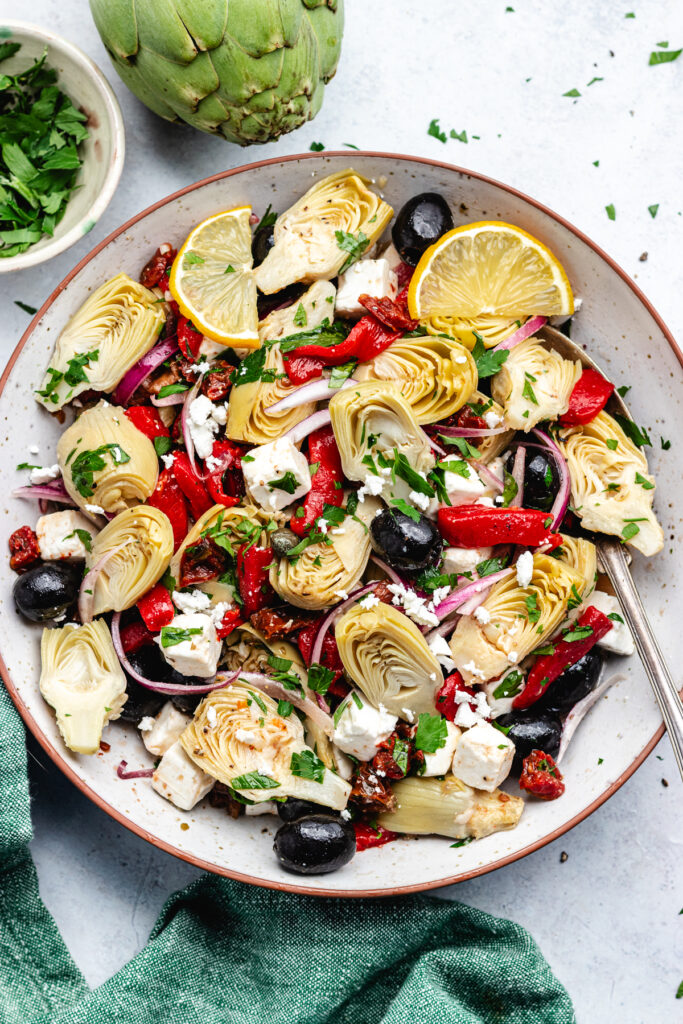 The artichoke salad in a bowl topped with lemon slices.