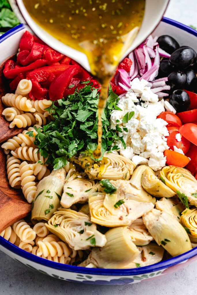 Pouring the dressing over the pasta salad.