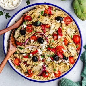 The pasta salad in a serving bowl topped wit fresh herbs.
