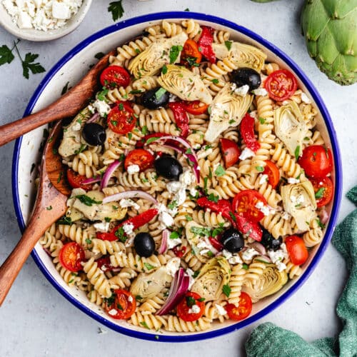 The pasta salad in a serving bowl topped wit fresh herbs.
