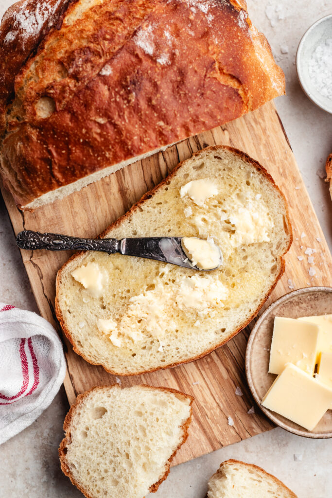 The sliced bread with butter on a wooden cutting board.