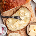 The sliced bread with butter on a wooden cutting board.