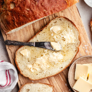 The sliced bread with butter on a wooden cutting board.