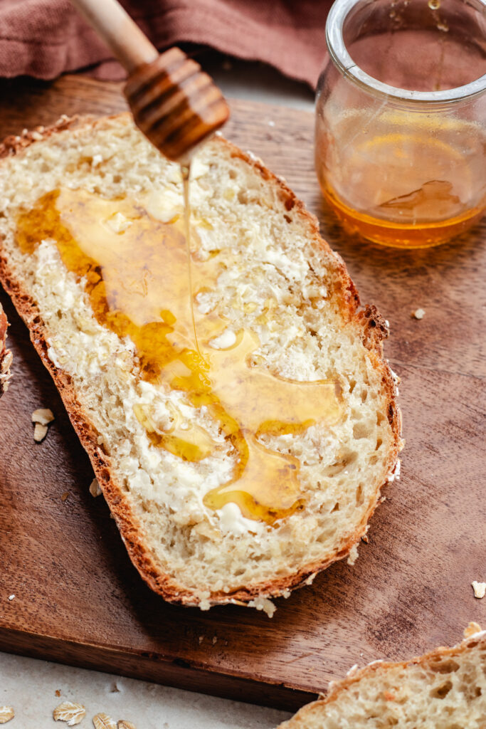 The oatmeal bread cut in slices topped with butter and honey.