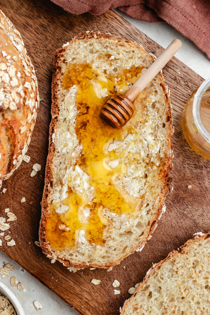 The oatmeal bread cut in slices topped with butter and honey.