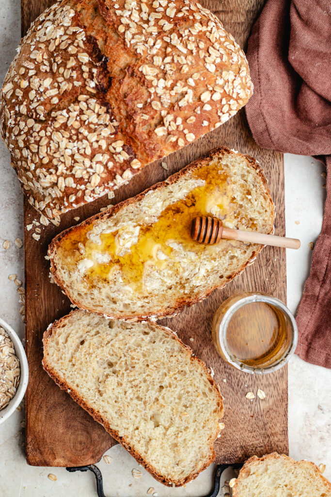 The oatmeal bread cut in slices topped with butter and honey.