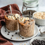 A glass filled with the overnight oats, topped with banana slices, peanut butter and chocolate chips.