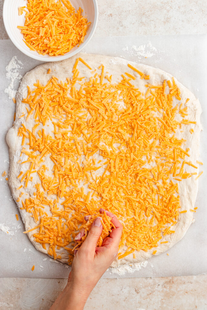 Covering the dough with the grated cheese.