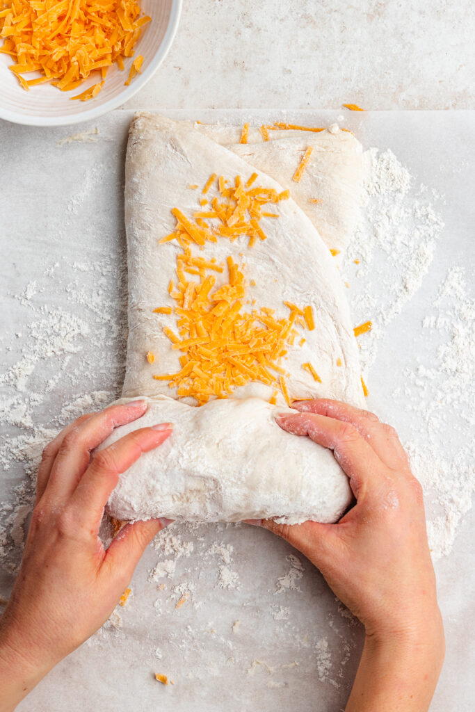 Rolling the dough with the grated cheese.