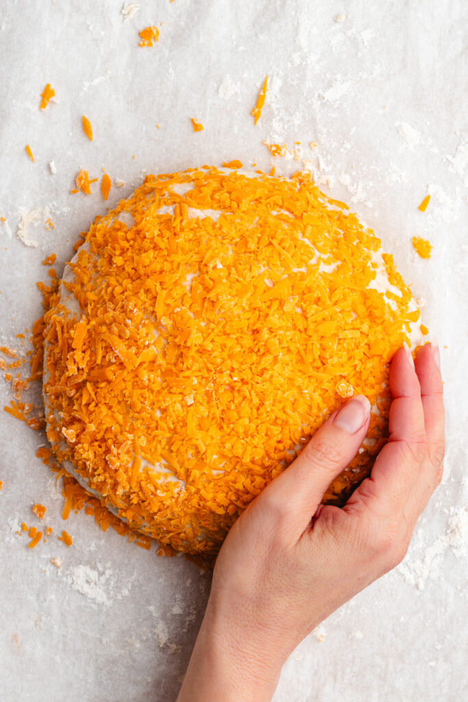Shaping the dough to a ball and topping it with more shredded cheese.