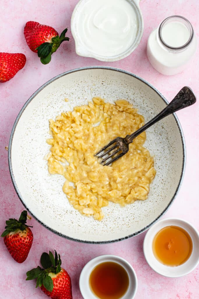 The mashed banana in a bowl with a fork.