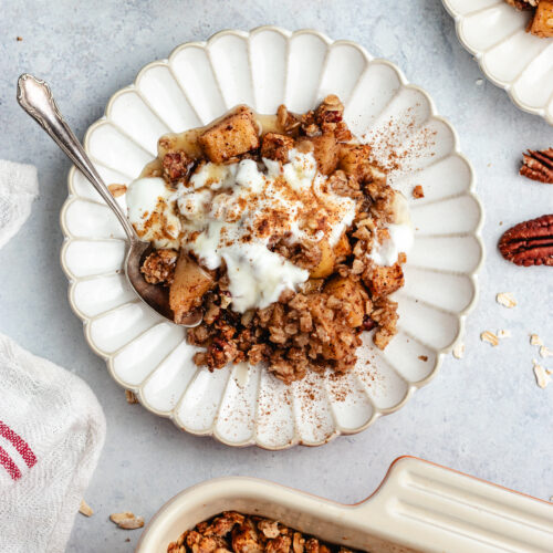 The crumble on a small plate topped with some yoghurt.