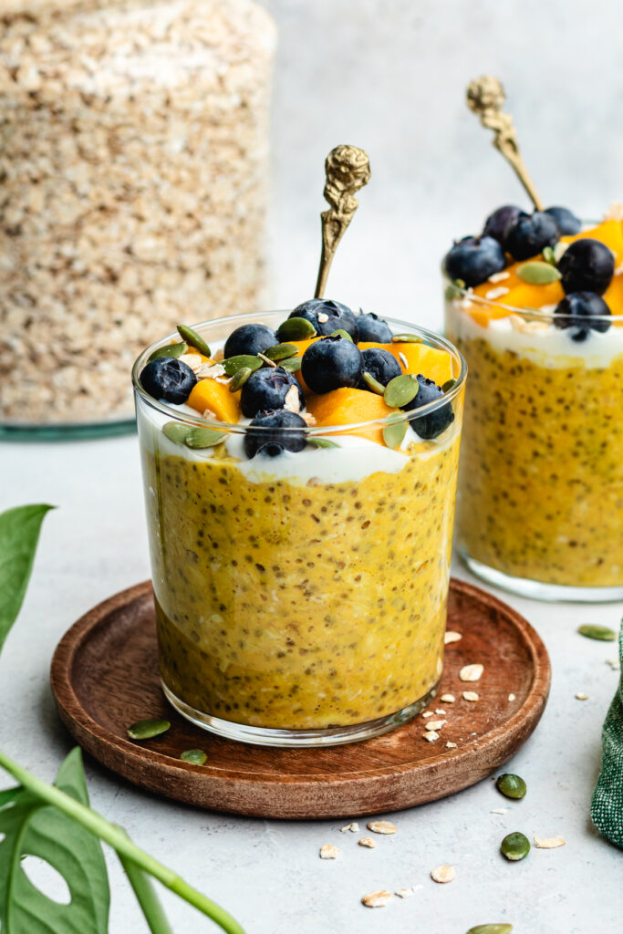 The overnight oats in two glasses topped with yoghurt and fresh fruit.