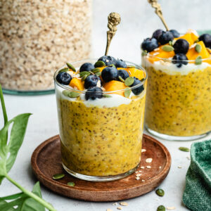 The overnight oats in two glasses topped with yoghurt and fresh fruit.