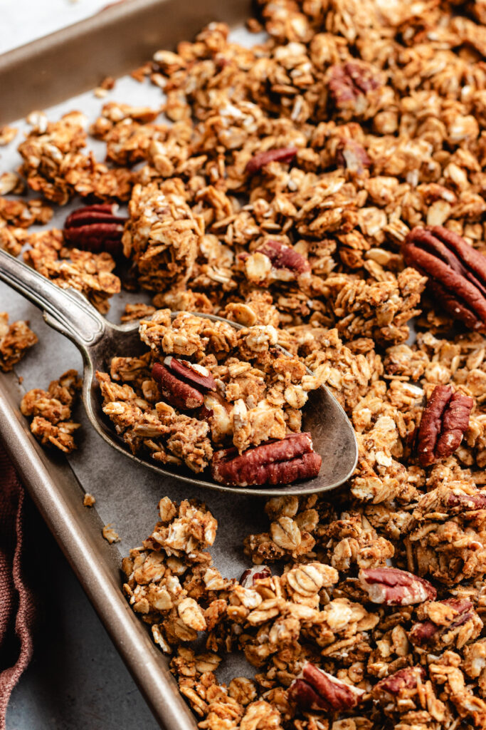 The granola on a baking sheet with a spoon.