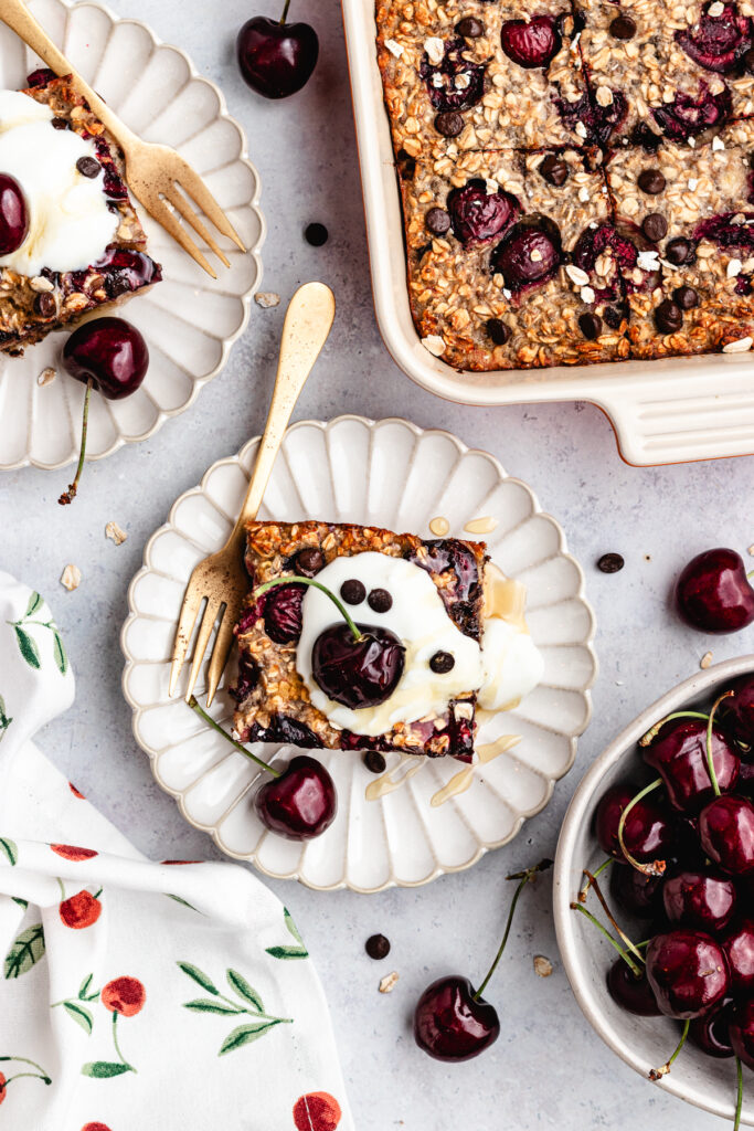 The overnight oats on two plates topped with yoghurt and fresh cherries.