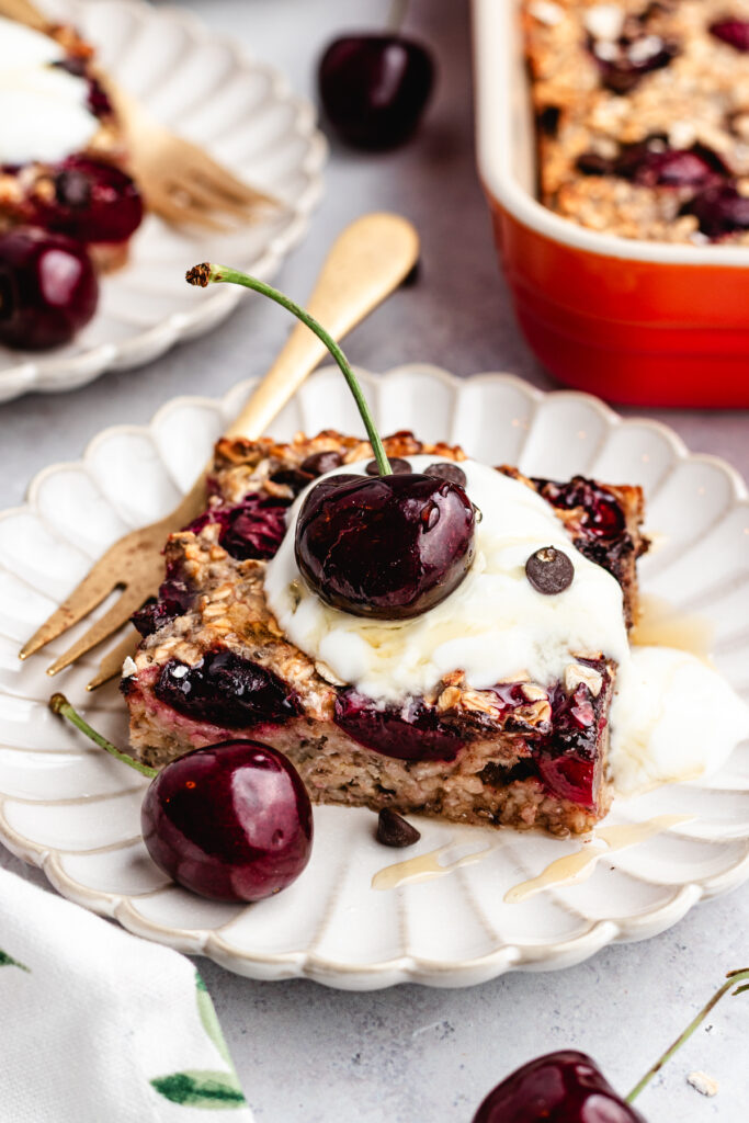 The overnight oats on two plates topped with yoghurt and fresh cherries.