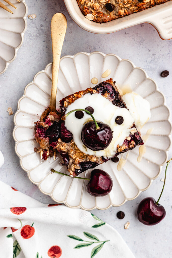The overnight oats on two plates topped with yoghurt and fresh cherries.