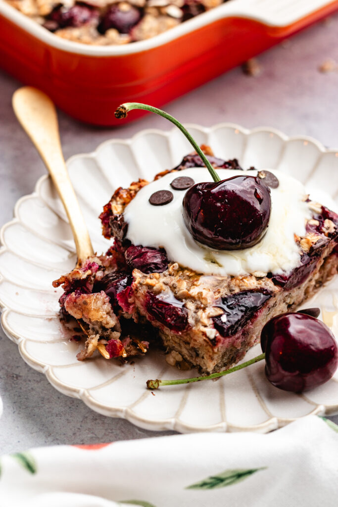 The overnight oats on a plate topped with yoghurt and fresh cherries.